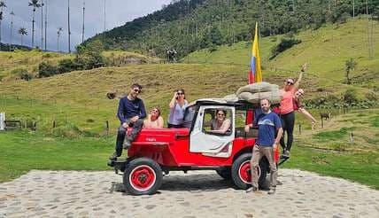 Viajeros junto a un jeep con bultos de café entre palmas de cera