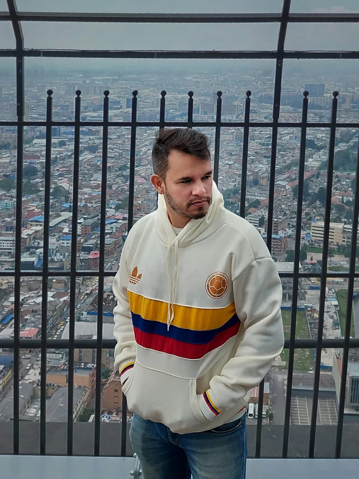 Andrés Jiménez de los Ríos en un mirador con vista a la ciudad, vistiendo una sudadera con los colores de Colombia.
