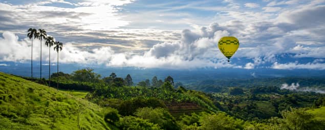 Hot air balloon flying over mountains and landscapes of the Coffee Region in Colombia