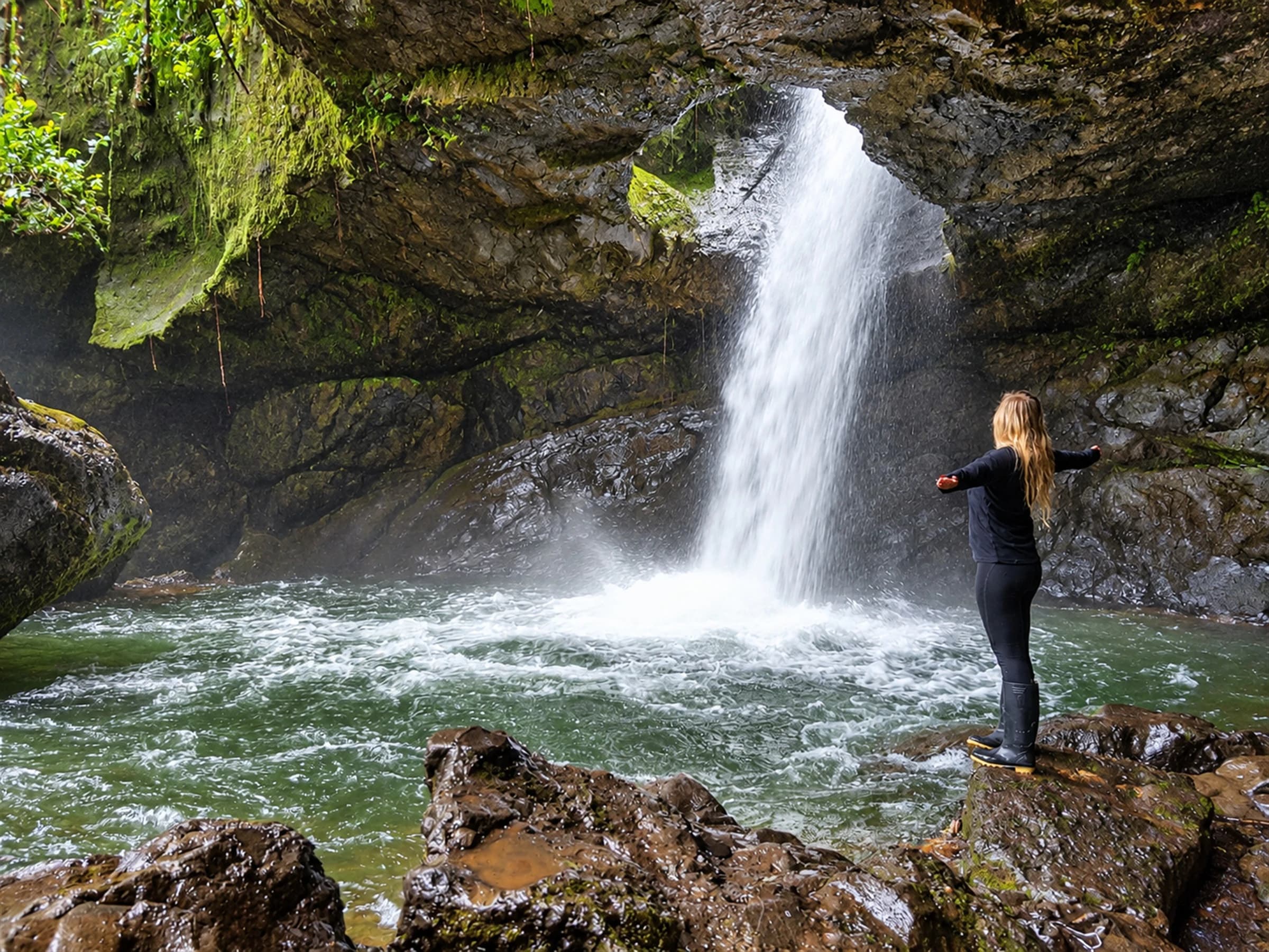 Waterfall inside a cavern at Cueva del Esplendor, with a person enjoying the landscape.