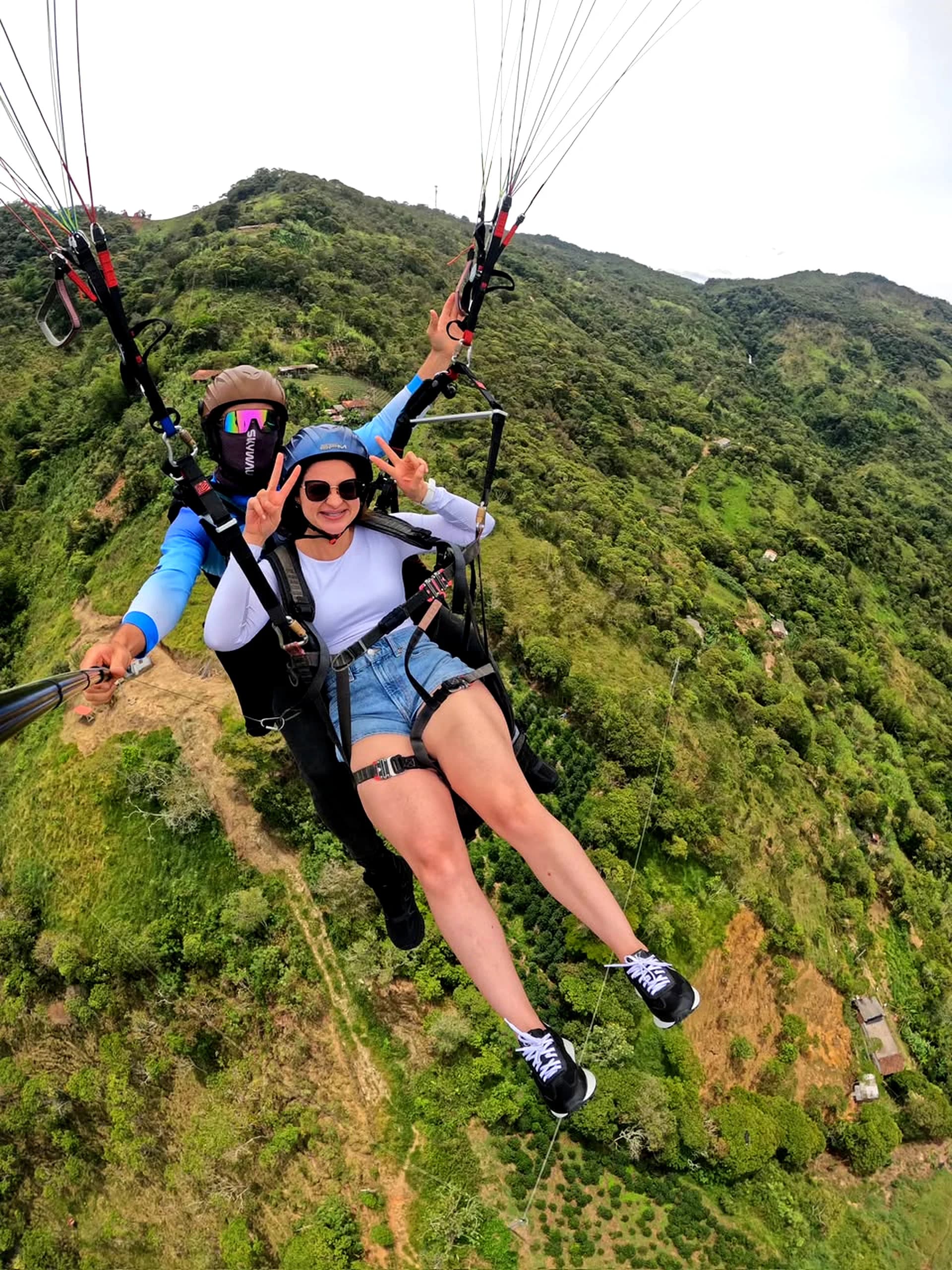 Paragliding over the mountains of Cocorná with two people enjoying the experience.