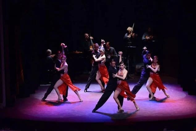 Tango dancers on a lit stage, showcasing a passionate choreography.