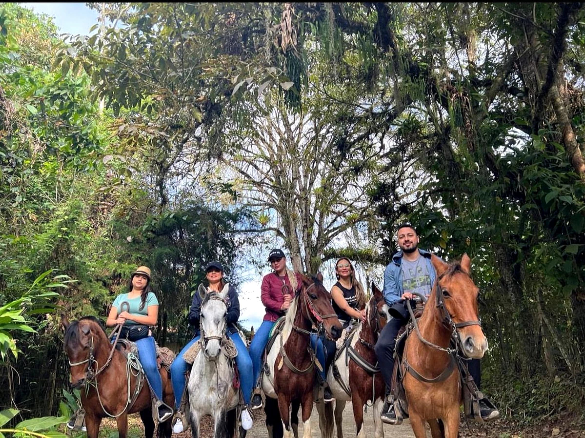 Grupo de personas montando a caballo en un sendero rural rodeado de naturaleza en Jardín, Antioquia.