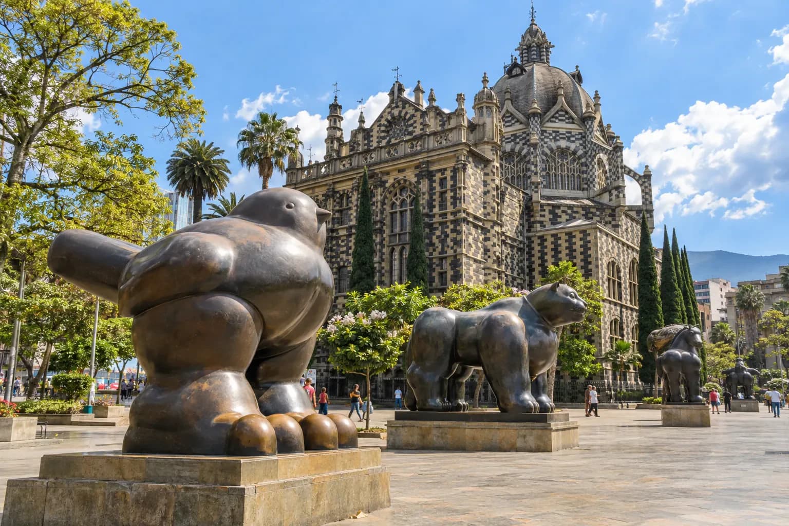 Plaza con esculturas de bronce frente a un edificio de franjas blancas y negras en el centro de Medellín