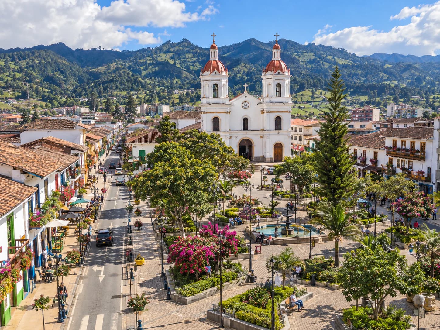 Vista panorámica de La Ceja con su plaza central y la iglesia rodeada de montañas y vegetación.